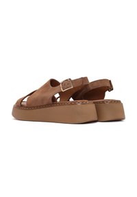 Sandali in suede marrone con punta aperta, design a ritagli, cinturino alla caviglia regolabile e suola spessa. Dettagli cuciti lungo i bordi.