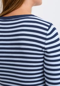 Sweter w paski w kolorze granatowym i jasnoniebieskim, o dopasowanym kroju, z prążkowanym dekoltem i bezszwowymi ramionami. Materiał wydaje się gładki i miękki.