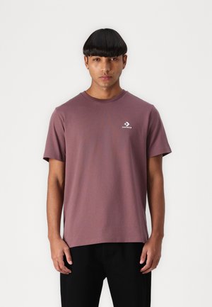 Bordeauxrotes T-Shirt mit kurzen Ärmeln aus Baumwolle, mit einem runden Halsausschnitt und einem kleinen weißen Converse-Logo auf der linken Brust.