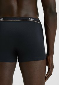 Dark blue boxer briefs with a fitted design, featuring a logoed waistband in contrasting color and smooth, stretch fabric.