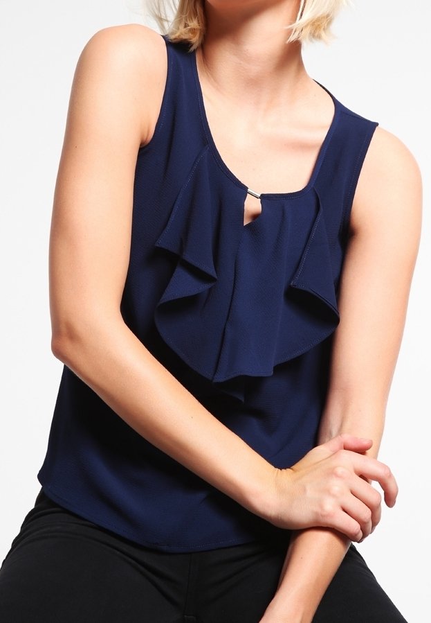 Námořnická modrá tílko bez rukávů s vrstvenými volány na přední straně, detaily ve tvaru klíčové dírky na výstřihu a hladkou texturou látky.