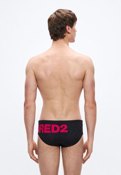 Črne plavalne kopalke z teksturiranim vzorcem in širokim roza trakom z napisom "ARED2" na zadnji strani. Brez drugih opaznih značilnosti.