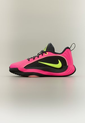 Basket Nike rose vif et noire avec un swoosh jaune néon et des lacets noirs, vue de côté sur un fond uni.
