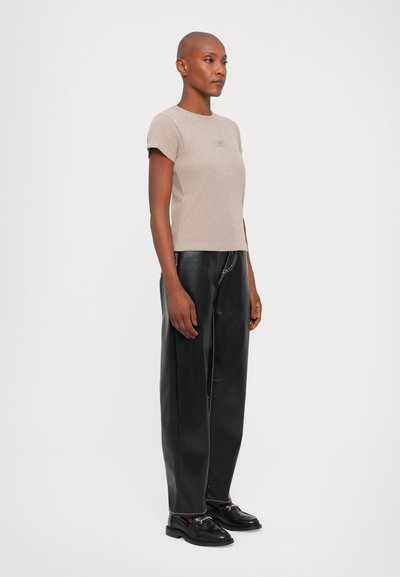 Beige fitted t-shirt with short sleeves, paired with high-waisted black leather trousers featuring contrast stitching and a straight-leg design.