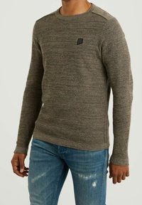 Langärmliger grauer strukturierter Pullover mit Rundhalsausschnitt, ausgestattet mit einem kleinen schwarzen Logo auf der Brust und gerippten Bündchen, kombiniert mit blauen Jeans.