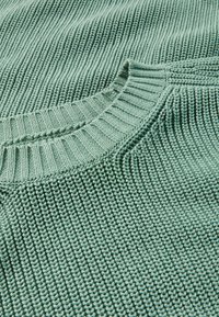 Hellgrüner Strickpullover mit geripptem Halsauschnitt und strukturiertem Muster. Verfügt über eine lockere Passform und eine weiche, baumwollartige Textur.