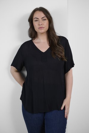 Blusa nera a scollo a V con maniche corte, realizzata in tessuto leggero. Presenta una sottile trama e un orlo dritto. Abbinata a jeans blu.