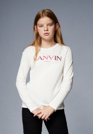 Langermet skjorte i hvit bomull med en teksturert rosa "LANVIN PARIS" logo over brystet. Modell iført svarte cordbukser.