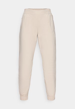 Beige joggerbukser med elastisk talje, to sidelommer og elastiske manchetter ved anklerne; glat, let materiale.