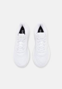 Zapatillas deportivas blancas con parte superior de malla, cierre de cordones, suela acolchada y acentos texturizados. Marca visible en la lengüeta.