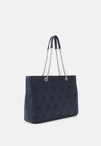 Marineblauwe tote bag van leer, met een geperst logopatroon, zilveren kettinghengsels en een gladde textuur. Rechthoekige vorm met afgeronde hoeken.