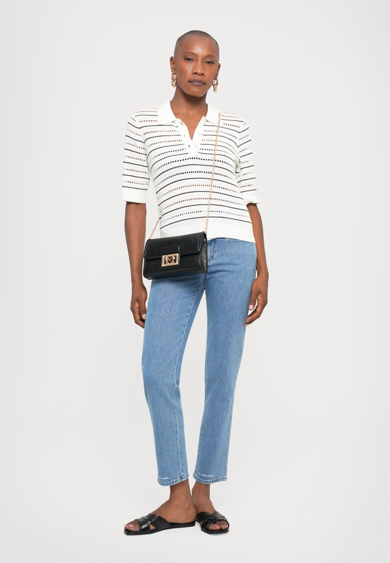 Polo à rayures blanches à manches courtes, associé à un jean droit bleu clair et un sac bandoulière noir. Des sandales noires complètent le look.