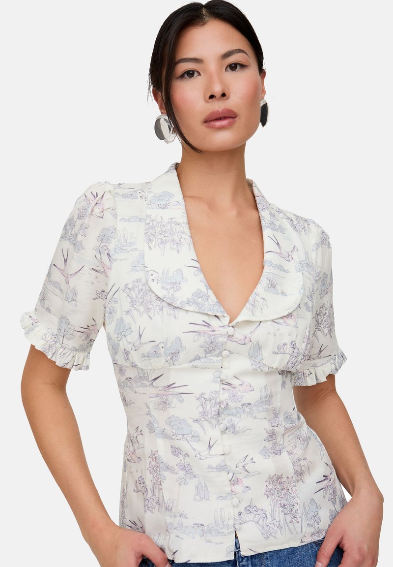 Floral button-up blouse in a light cream fabric with purple and blue patterns. Features short ruffled sleeves and a large collar.