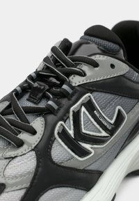 Αθλητικό παπούτσι σε γκρι και μαύρο με πλέγμα και συνθετικά υλικά, διαθέτει λεπτομέρεια με λογότυπο, υφασμένες κορδόνια και μαξιλαρωμένη σόλα.