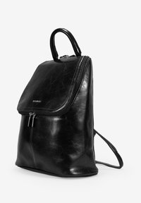 Mochila de cuero negro con un acabado liso, cierre de cremallera y un asa en la parte superior. Cuenta con correas delgadas para los hombros y un diseño minimalista.