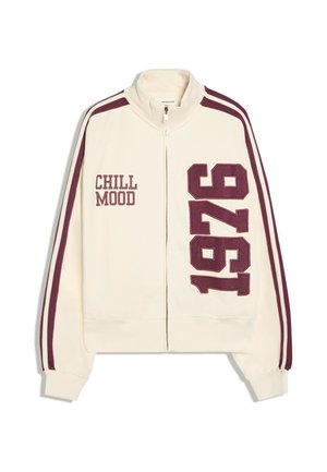 Veste crème zippée avec des bandes bordeaux sur les manches, texte "CHILL MOOD" sur la poitrine gauche et grand "1976" à l'avant droite.