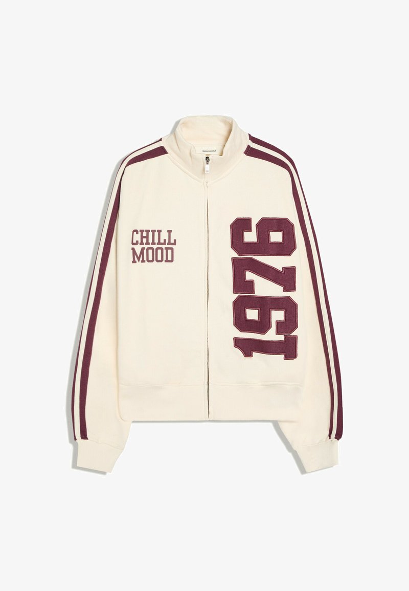 Veste crème zippée avec des bandes bordeaux sur les manches, texte "CHILL MOOD" sur la poitrine gauche et grand "1976" à l'avant droite.