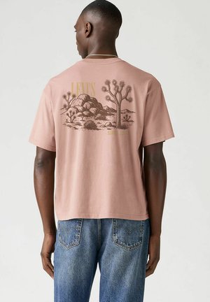 Roze katoenen T-shirt met korte mouwen, met een graphic van een woestijnscène in bruin en "Levi's" tekst op de bovenrug. Casual pasvorm.