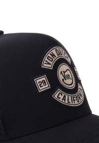 Juodas beisbolo kepurė su išsiuvinėtu grietinėlės spalvos logotu, kuriame yra tekstas "Von Dutch California" ir skaičius "29" apvalaus dizaino.