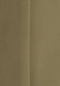 Groene katoenen stof met een subtiele textuur, met een dichtgeweven ontwerp. Het oppervlak lijkt glad en uniform met minimale patronen.