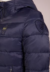 Giacca imbottita blu navy con trapuntatura imbottita, etichetta Blauer USA sul petto e toppa ricamata Blauer sulla parte superiore della manica.