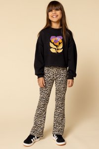 Zwarte cropped sweatshirt met een paarse en gouden bloemenontwerp, gecombineerd met leopardenprint flared broeken en zwarte sneakers met witte strepen.