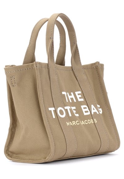 Saco de tela bege com duas alças e texto branco a dizer "THE TOTE BAG MARC JACOBS" na parte da frente.
