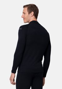 Czarna koszula z długim rękawem wykonana z gładkiego materiału, z okrągłym dekoltem i subtelnymi detalami przeszycia, dopasowany krój oraz logo na ramieniu.