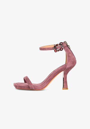 Sandale à talons hauts en suède mauve avec une fine bride sur le devant, une bride de cheville ornée de pierres précieuses rouges et une fermeture éclair à l'arrière.