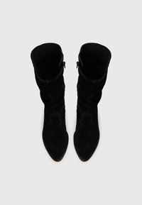 Bottes noires en daim jusqu'au genou avec un design décontracté, bout pointu et zips latéraux. Texture lisse et style minimaliste sans accents visibles.