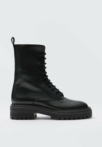 Czarne skórzane bootsy na sznurówki o teksturowanym wykończeniu, wysokość do połowy łydki, z grubą gumową podeszwą oraz pętelką z tyłu ułatwiającą zakładanie.