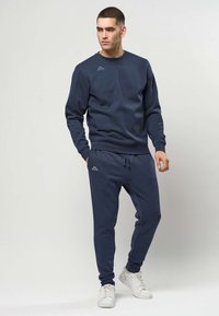 Marineblå genser og joggebukse i myk bomull, med ribbestrikkede mansjetter, snøring i livet, og en liten logo på hver del.