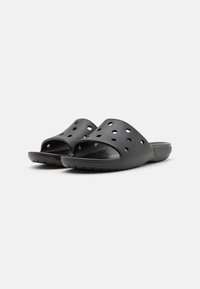 Chanclas negras de plástico, con grandes agujeros de ventilación, diseño abierto en la parte delantera, plantilla texturizada y suela de goma con un patrón.