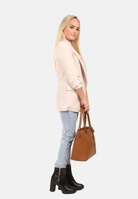 Beige blazer, lichtblauwe jeans, zwarte enkelboots. Bruine handtas met twee handvatten, een gladde textuur en accenten van zilver hardware.