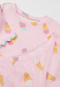 Svetle růžový bavlněný outfit s motivy zmrzlinových kornoutů, se župánkovými rukávy a elastickým pasem. Měkká textura s hravým designem.