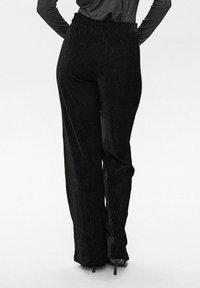 Zwarte wijde broek met een textuurstof en een elastische tailleband. Het ontwerp is ontspannen, wat zorgt voor een comfortabele pasvorm.