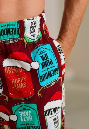 Rote und türkisfarbene Schlafanzughosen mit einem festlichen Druck von Bierdosen und Weihnachtsmannhüten, aus einem weichen, leichten Stoff mit elastischem Bund.