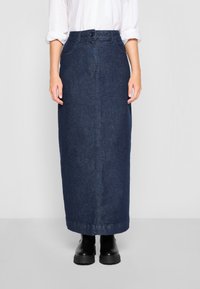 Jeansmaxikjol i mörkblått med frontknäppning, bältesöglor, sidofickor och rak passform. Matchad med svarta kraftiga stövlar.