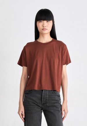 Roestkleurig crop t-shirt van zachte stof met een ronde halslijn en korte mouwen, gecombineerd met donkergrijze hoge taille spijkerbroek.
