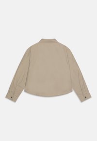 Lichtbeige overhemd met lange mouwen, voorzien van een kraag, knoopsluiting bij de manchetten en een gebogen zoom. Gemaakt van zachte, gestructureerde stof met een subtiel patroon.