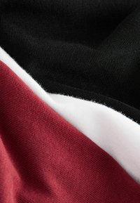 Medvilninė medžiaga su juodais, baltais ir burgundiškais segmentais. Lygi tekstūra su aiškiais spalvų blokais ir minkštu paviršiumi.