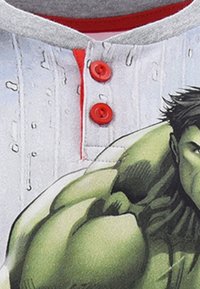 Camicia bianca a maniche corte con grafica di un personaggio dei cartoni animati verde, bottoni rossi e colletto grigio. Il tessuto sembra morbido e dalla texture liscia.