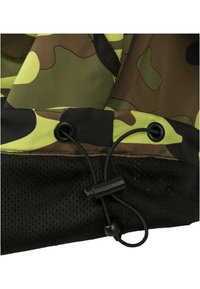 Kamouflagemönstrad tyg i nyanser av grönt och brunt, med en svart nätsektion och en svart cord lock för justering.