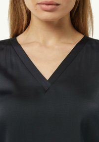 Schwarzes Satin-Top mit V-Ausschnitt und glatter Textur. Der Stoff wirkt weich mit einem subtilen Glanz.