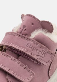 Pantofii din piele mov cu căptușeală moale, având accente în formă de urs și curele cu arici. Design simplu cu detalii cusute.