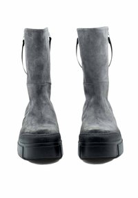Bottes à cheville en daim gris avec une semelle noire épaisse, dotées d'une languette à l'arrière et d'une texture lisse. Le design est minimaliste et moderne.