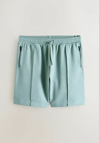 Lyseblå herreshorts med elastisk talje, snøre og to lodrette lynlåslommer på en neutral baggrund.