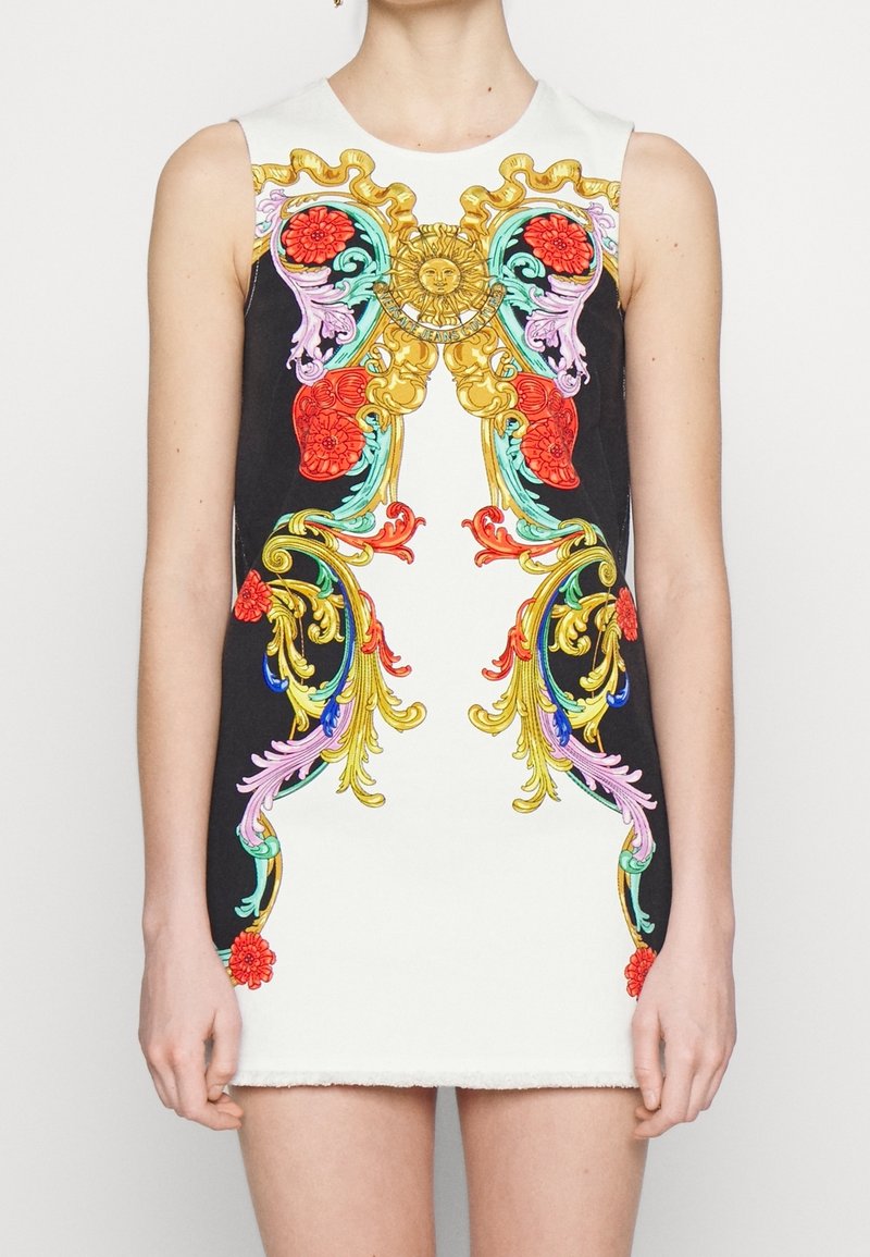 Mouwloze witte jurk met levendige barokstijl bloemen- en krulpatronen in rood, goud, turkoois en paars, met een centraal zonmotief.