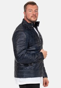 Marine leren jas met hexagonale quilting, een hoge kraag, ritszakken en een getailleerd ontwerp, met een gladde textuur en een glanzende afwerking.