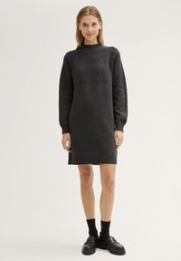 Abito lavorato a maglia grigio scuro con texture a costine, collo alto e maniche lunghe. Presenta un pannello liscio a contrasto nella parte superiore e orlo aderente.